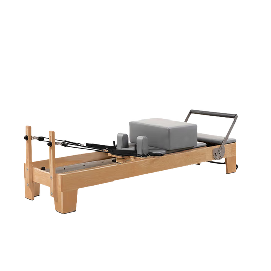 Side view of the Classic Oak Core Pilates Reformer with grey padding, showing oak wood frame and carriage system